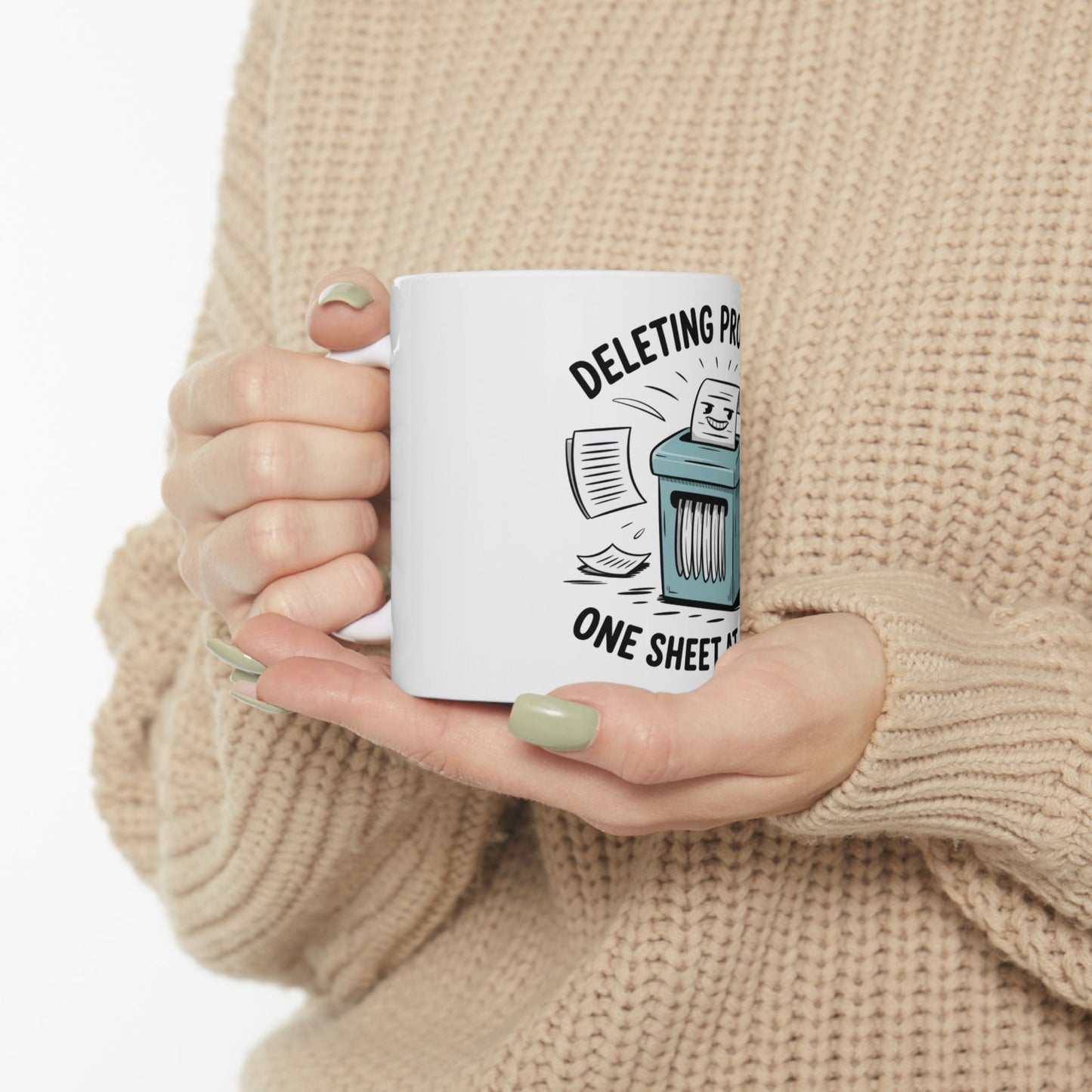 White mug with cartoon shredder and text "DELETING PR ONE SHEET AT A TIME".